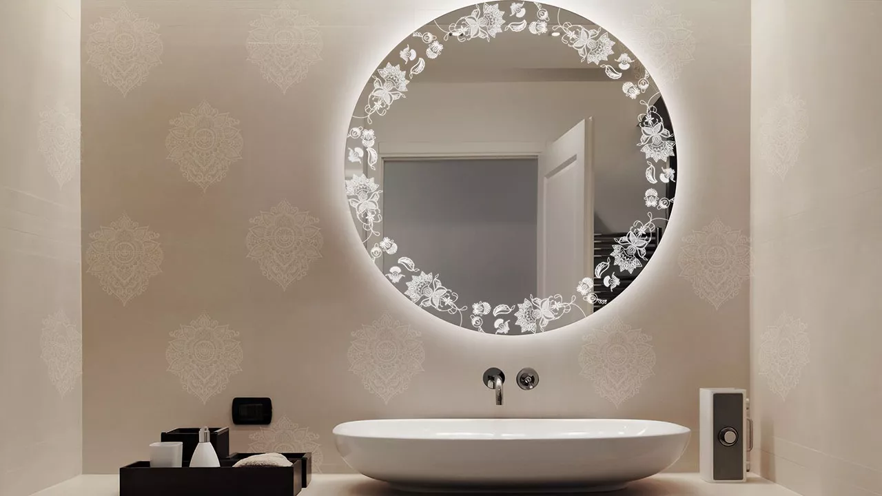 Compact of a backlit mirror with paisley design above a plain white oval washbowl in Abu Dhabi.