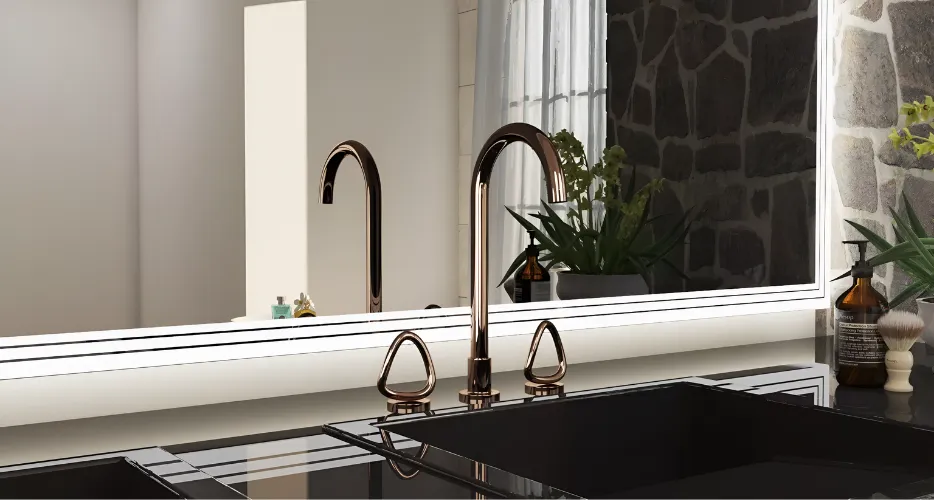 Copper curved faucet with matching triangular handles above a black glass sink in a modern bathroom, reflected in a large backlit mirror with a stone wall backdrop.