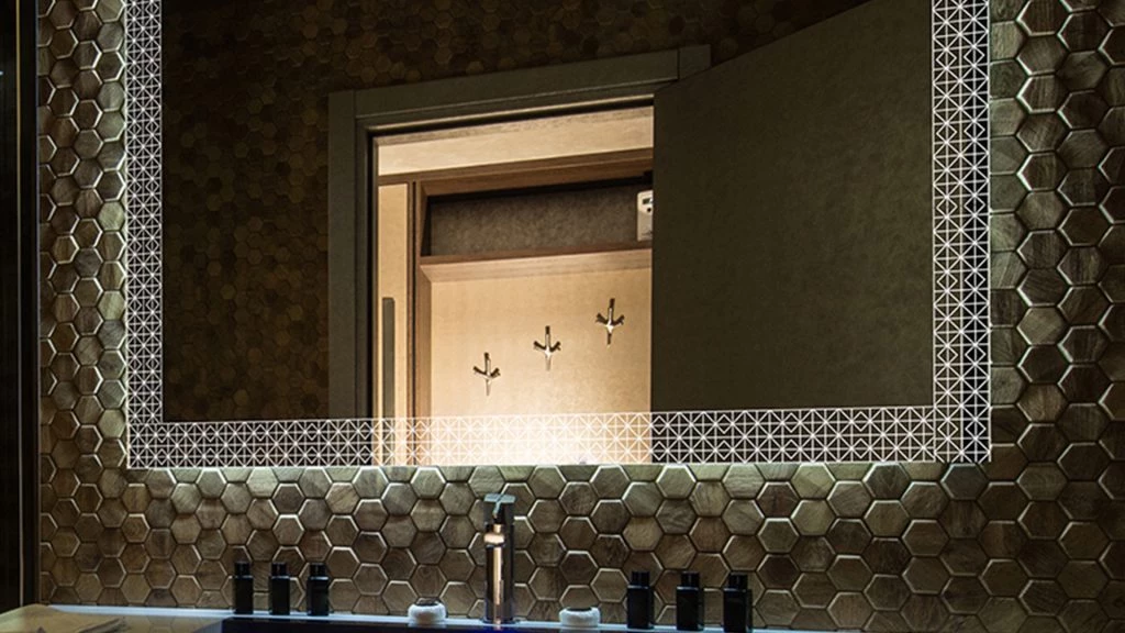 Wooden mosaic wall mounted with a light up mirror with geometrical pattern and a sink in Dubai.