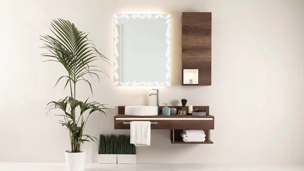 Front lit mirror attached to a white concrete wall with a wooden cabinet and plants below in Al Ain.